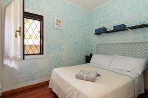 A bedroom with a bed, a window with curtains, a nightstand, and a wall-mounted shelf. - Casa Pinta by Wonderful Italy (Arzachena)