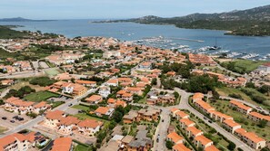 An aerial view of a coastal town with residential buildings, a marina, and a clear view of the sea. - Casa Pinta by Wonderful Italy (Arzachena)