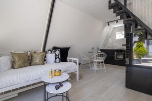 Eine moderne Loftwohnung mit Schlafgalerie, einer kleinen Essecke und einer Küche inklusive Backofen.
