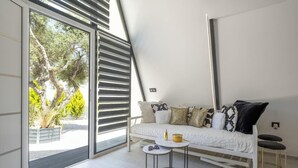 A modern room with a bed, a small round table, and a large window with blinds. - A truly distinctive retreat where contemporary design,natural beauty. (Chania)