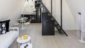 A loft-style apartment with a staircase connecting two levels, a kitchen area, and a seating area with a sofa and small tables. - A truly distinctive retreat where contemporary design,natural beauty. (Chania)