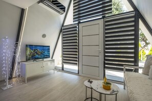 Ein modernes Schlafzimmer mit Schräge, einem Bett, einem kleinen Tisch, einem Fernseher und einem Kleiderschrank.