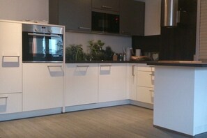 Eine moderne Küche mit weißen Schränken, einem eingebauten Backofen, einer Mikrowelle und einer Edelstahl-Dunstabzugshaube.