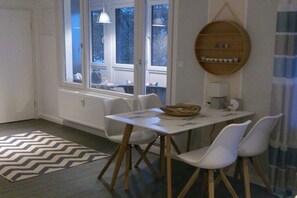 Ein Essbereich mit Tisch und Stühlen, ein Fenster mit Aussicht und einem an der Wand befestigten Regal.