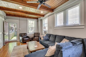 Ein Wohnzimmer mit Holzbalkendecke, einem grauen Sofa, einem braunen Ledersessel und einem Holztisch.