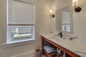 Ein Badezimmer mit Fenster, Waschbecken, Spiegel und Handtuchhalter.