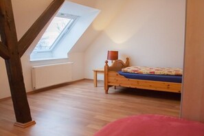A bedroom with a sloped ceiling, a wooden bed, a bedside table, a lamp, and a window. - 3 on the farm of Wattenmeer Ferien (Butjadingen)