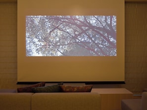 A projection screen displaying a tree with branches, a sofa with cushions, and a wooden wall.