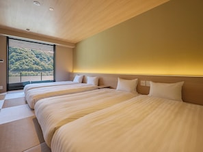 Une chambre d’hôtel avec trois lits, une grande fenêtre et une vue sur une zone boisée.