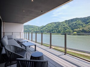Ein moderner Balkon mit Blick auf einen See und bewaldete Hügel.