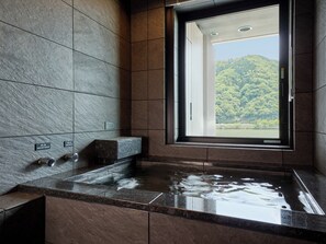 Ein modernes Badezimmer mit großem Fenster, einer Badewanne und einem Waschbecken.