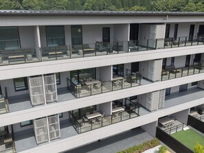 Ein mehrstöckiges Gebäude mit Balkonen, großen Fenstern und Außenbereichen zum Sitzen.