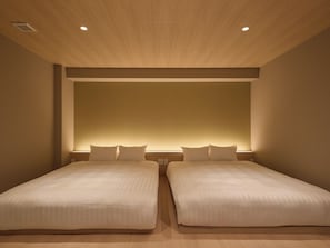 Une chambre d’hôtel avec deux lits, un plafond en bois et un éclairage encastré.