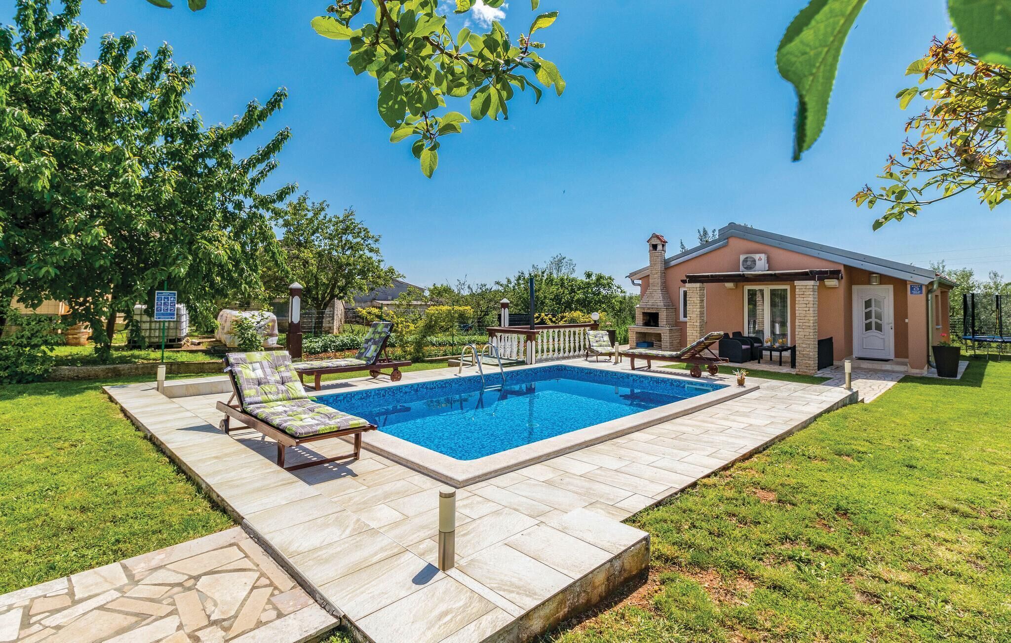 Ein Garten mit Swimmingpool, Liegestühlen, Grill und einem kleinen Gebäude mit Schornstein.