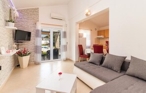 A living room with a sofa, a coffee table, a TV, and a dining area with chairs and a table. - Stunning home in Pula with private swimming pool, can be inside or outside (Pula)