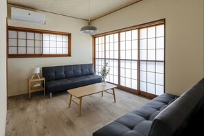 Een kamer met een bank, een klein tafeltje, een lamp en grote ramen met uitzicht.