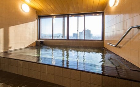 A hot tub with a city view, wooden ceiling, and tiled walls.