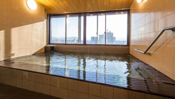 A hot tub with a city view, wooden ceiling, and tiled walls. - HOTEL LiVEMAX Tottori GRANDE (Tottori)