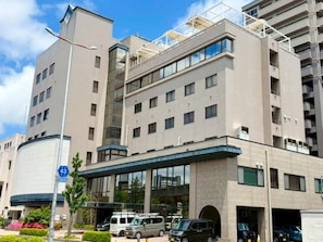 A multi-story hotel with a modern design, featuring a central atrium, parking garage, and a clear sky. - HOTEL LiVEMAX Tottori GRANDE (Tottori)