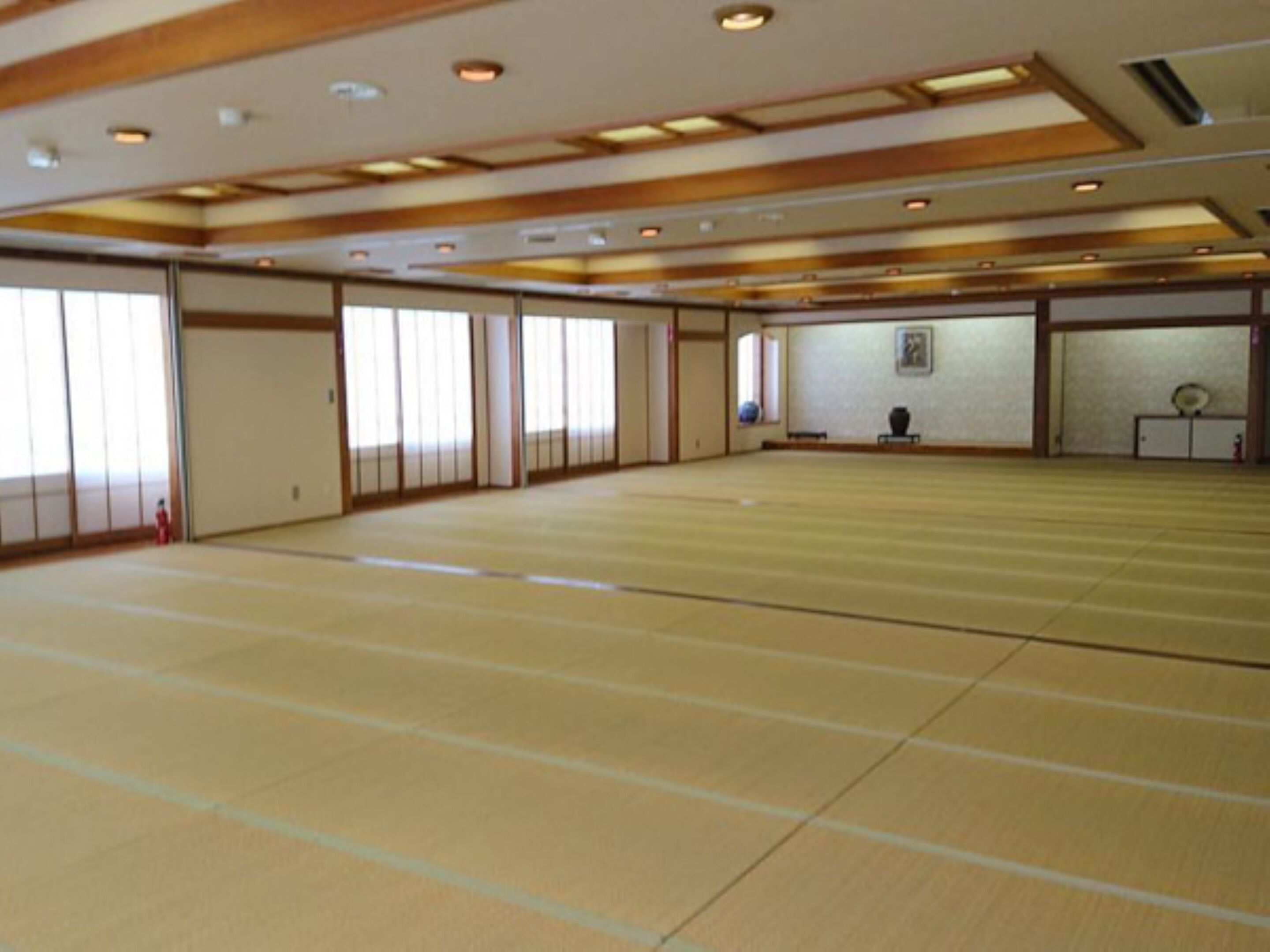 A large room with tatami mat flooring, sliding doors, and a traditional Japanese aesthetic.