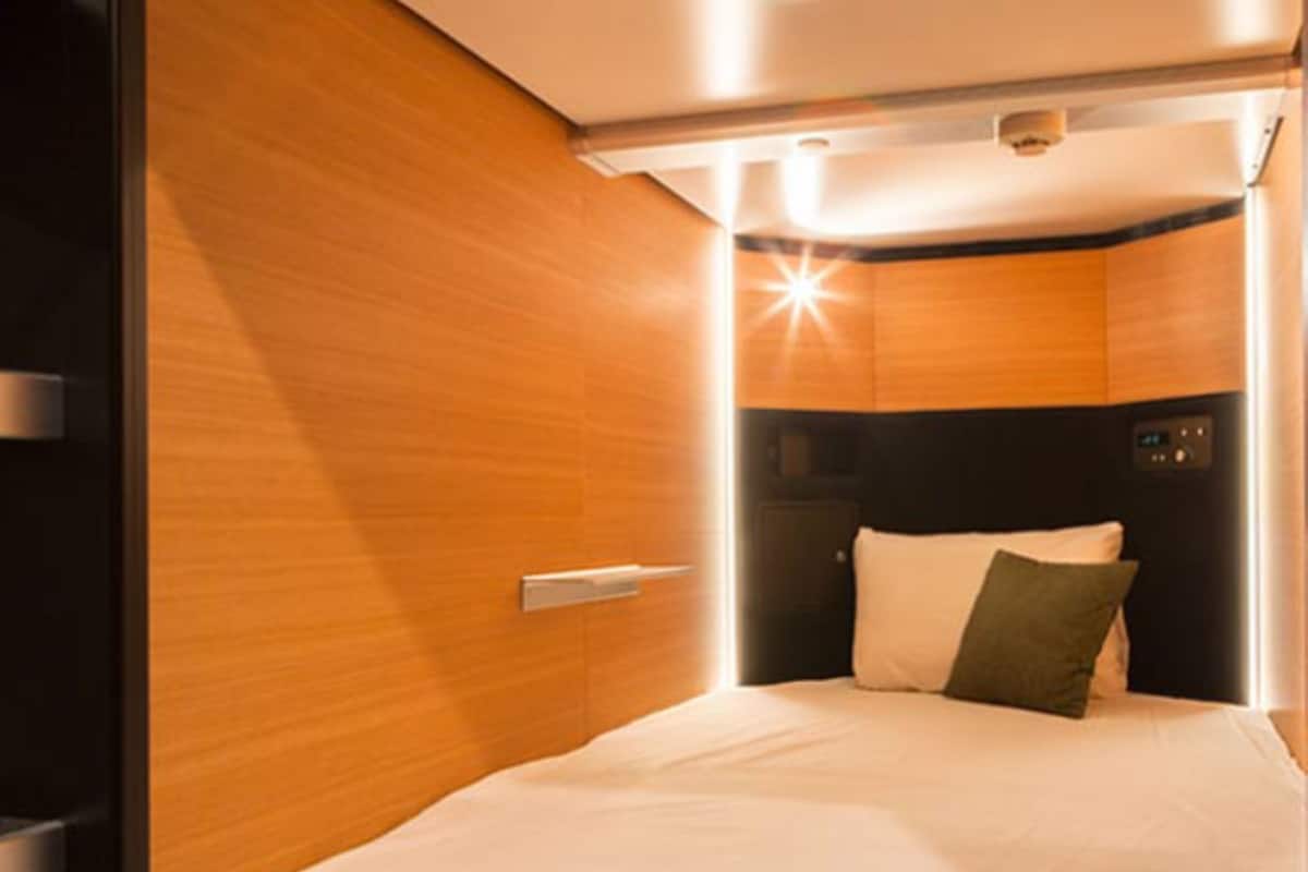 Una habitación moderna y compacta con una cama, un panel de control y una pared de madera.