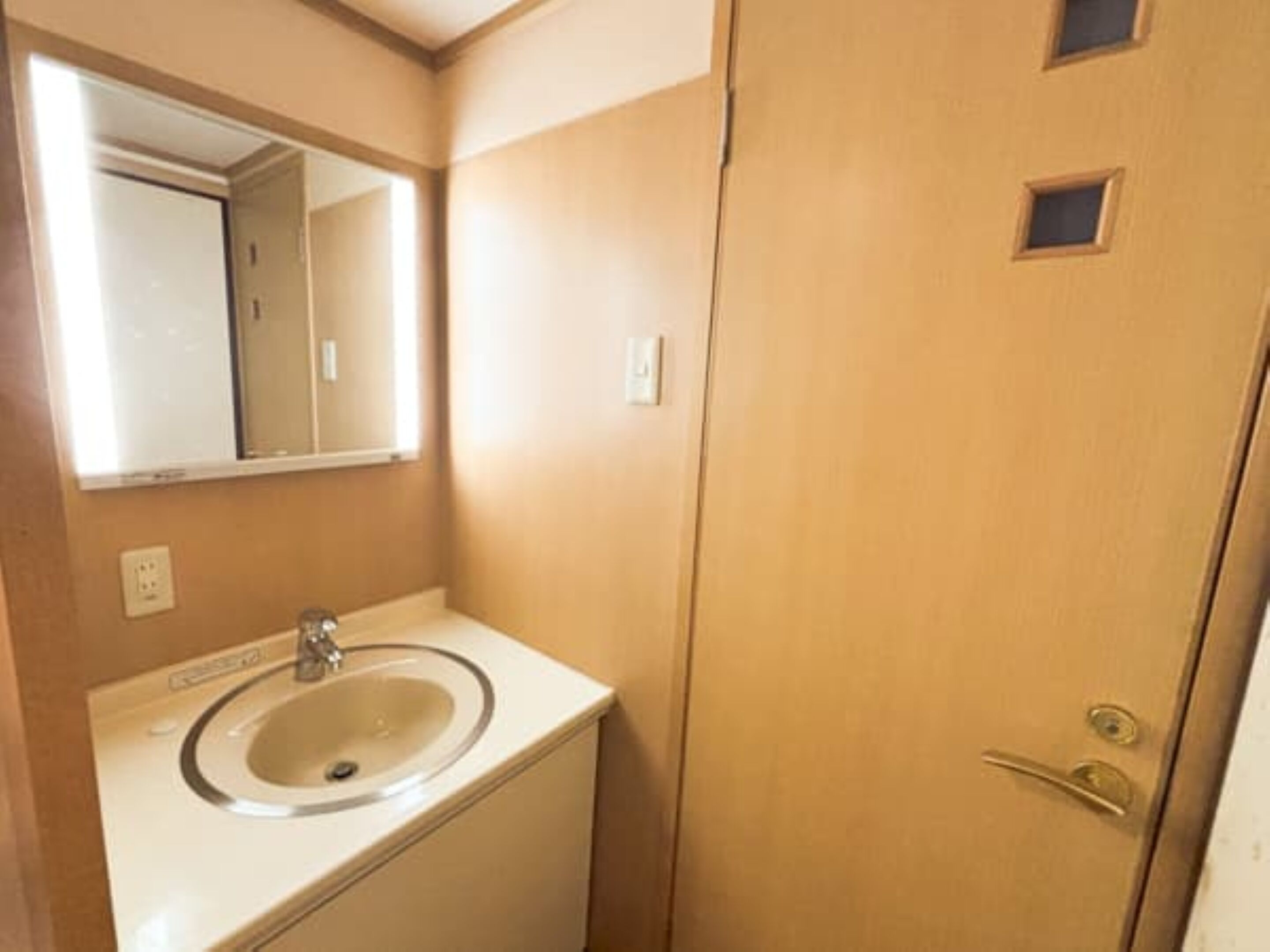 Une salle de bain avec un lavabo, un miroir et une porte.