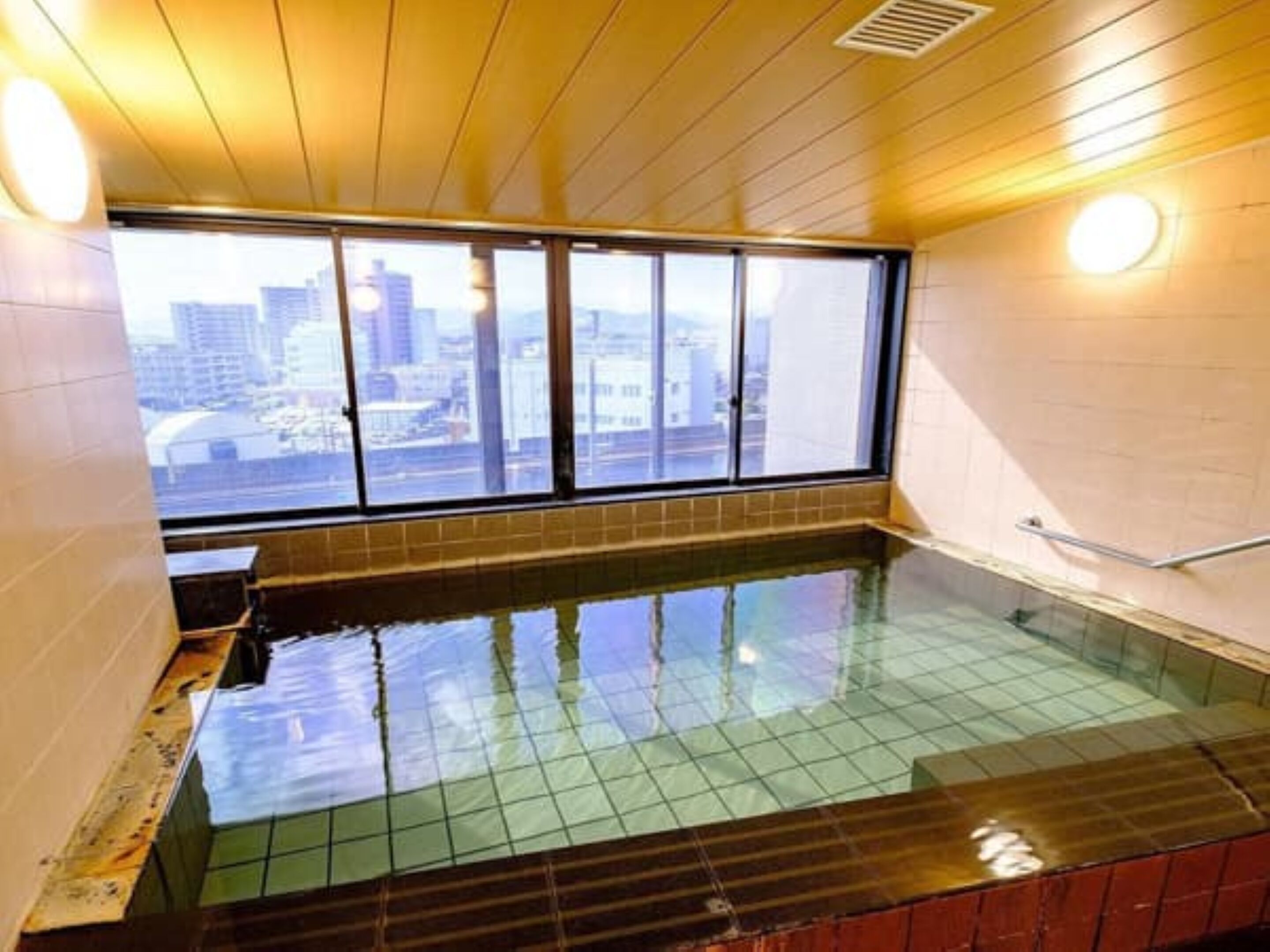 A room with a large window, a tiled floor, and a small pool.