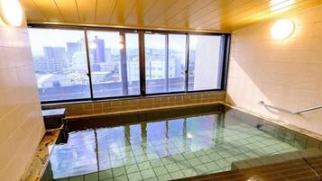 A room with a large window, a tiled floor, and a small pool.