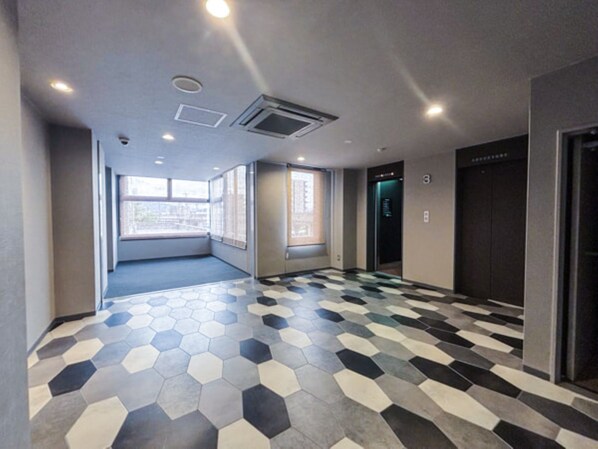 A hallway with a geometric patterned floor, a window, and an elevator.