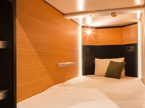 A compact, modern room with a bed, a control panel, and a wooden wall. - HOTEL LiVEMAX Tottori GRANDE (Tottori-shi)