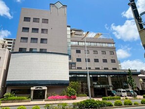 A multi-story building with a curved facade, large windows, and a gated entrance. - HOTEL LiVEMAX Tottori GRANDE (Tottori-shi)
