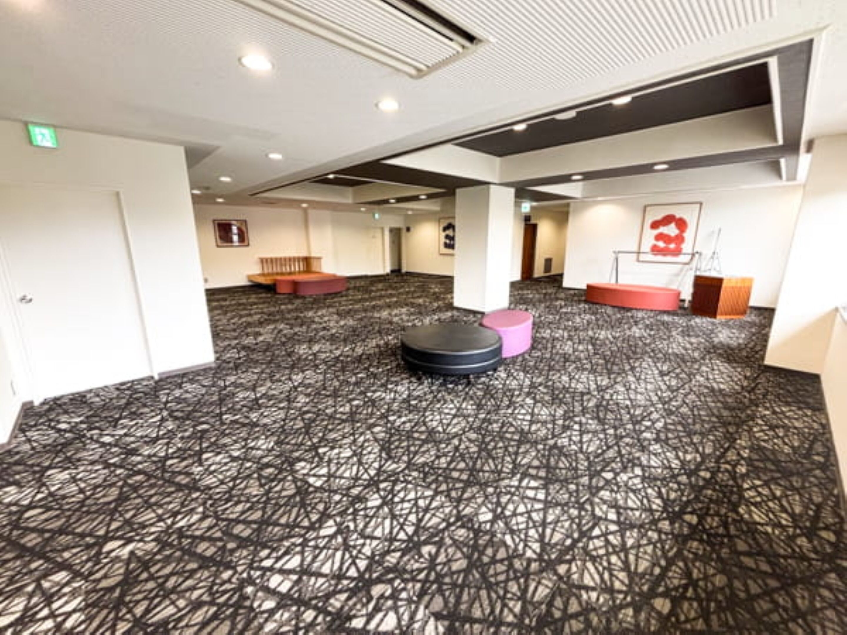 Un vaste espace intérieur doté d’un tapis à motifs, de différents types de sièges et d’un plafond pourvu d’un éclairage encastré.