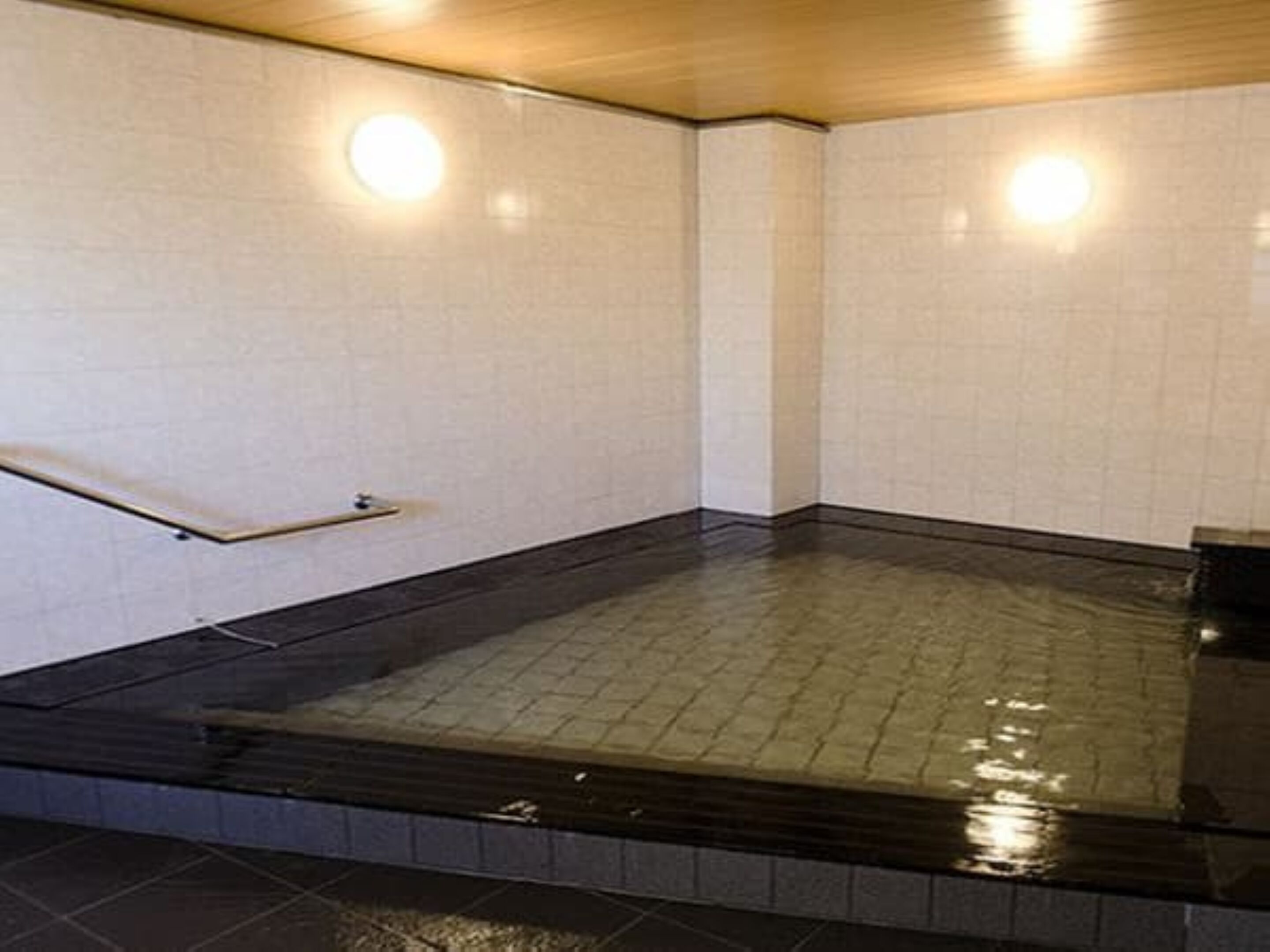A room with a tiled floor, a wooden ceiling, and a handrail.