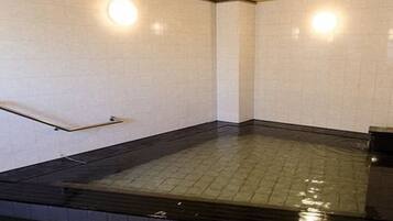 A room with a tiled floor, a wooden ceiling, and a handrail.