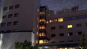 A modern hotel with multiple floors, large windows, and a starry night sky visible through the windows. - HOTEL LiVEMAX Tottori GRANDE (Tottori)