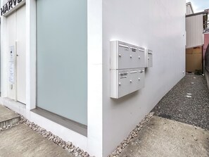 Ein Gebäudefassadenschild mit dem Schriftzug 'HARVE', ein Verteilerkasten mit nummerierten Fächern sowie ein Kiesweg.