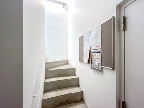 Eine schmale Treppe mit einer weißen Wand und einer Tür rechts.