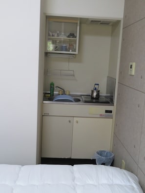 Eine kleine Küchenzeile mit Spüle, einem Schrank und einem Mülleimer.