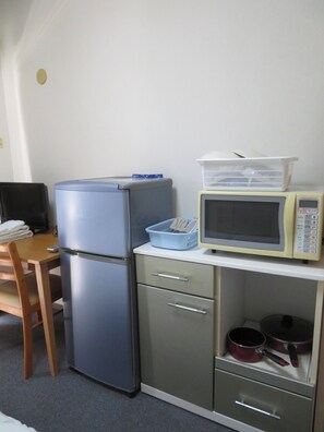 Eine kleine Küchenzeile mit Kühlschrank, Mikrowelle und Herd.
