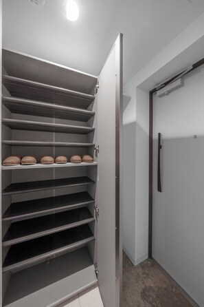 Ein Vorratsraum mit mehreren Regalen, einer Tür und einem Kühlschrank.