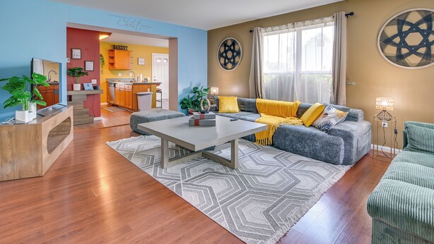A living room with a sofa, coffee table, and a kitchen in the background.