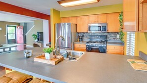 A modern kitchen with stainless steel appliances, a large island, and wooden cabinets.