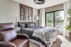 A bedroom with a bed, a chair, a nightstand, a lamp, a painting, and a balcony with a view. - Private Dock & Boat Slip! Belleville Lake Escape (Belleville)