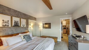 Ein Schlafzimmer mit Bett, Kommode, Fernseher und gerahmten Bildern an der Wand.
