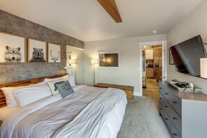 Ein Schlafzimmer mit Bett, Kommode, Fernseher und gerahmten Bildern an der Wand.