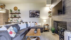 Ein modernes Wohnzimmer mit einem Ecksofa, einem Couchtisch, einem Kamin und Wanddekoration.