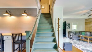 A staircase with a light blue finish, a dining area with two chairs and a small table, a sofa, and a ceiling fan. - Guest House w/ Private Pond & Dock in Southbury! (Southbury)