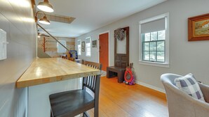 A spacious room with a wooden floor, a dining area with a wooden table and chairs, a large window, and a painting on the wall. - Guest House w/ Private Pond & Dock in Southbury! (Southbury)