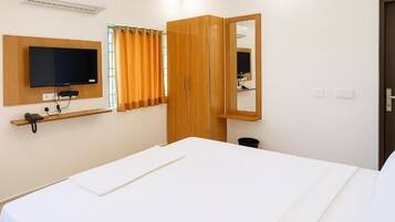 Una habitación de hotel con cama, televisor montado en la pared, armario y espejo.