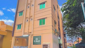 Un edificio de varios pisos con un letrero que dice 'Py Olliv' en la planta baja, una entrada con portón y un cielo despejado al fondo.